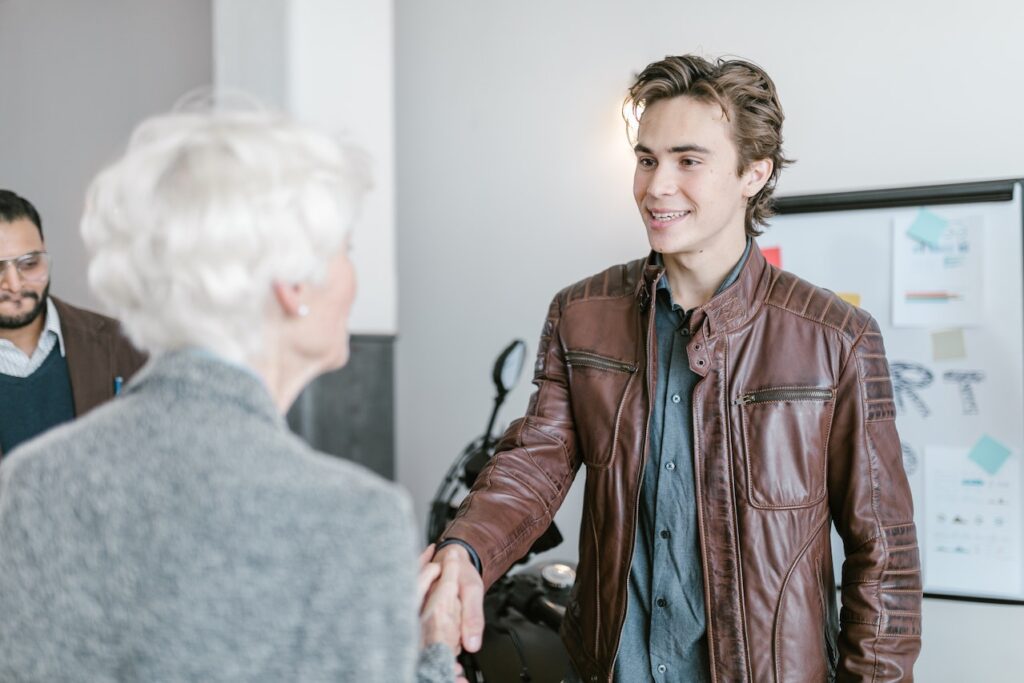Young man shakes hands with older woman in an office