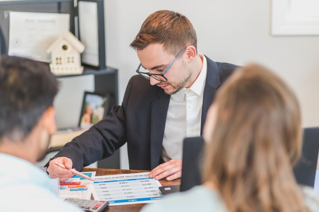 Real estate agent sitting and explaining financial paperwork to a couple